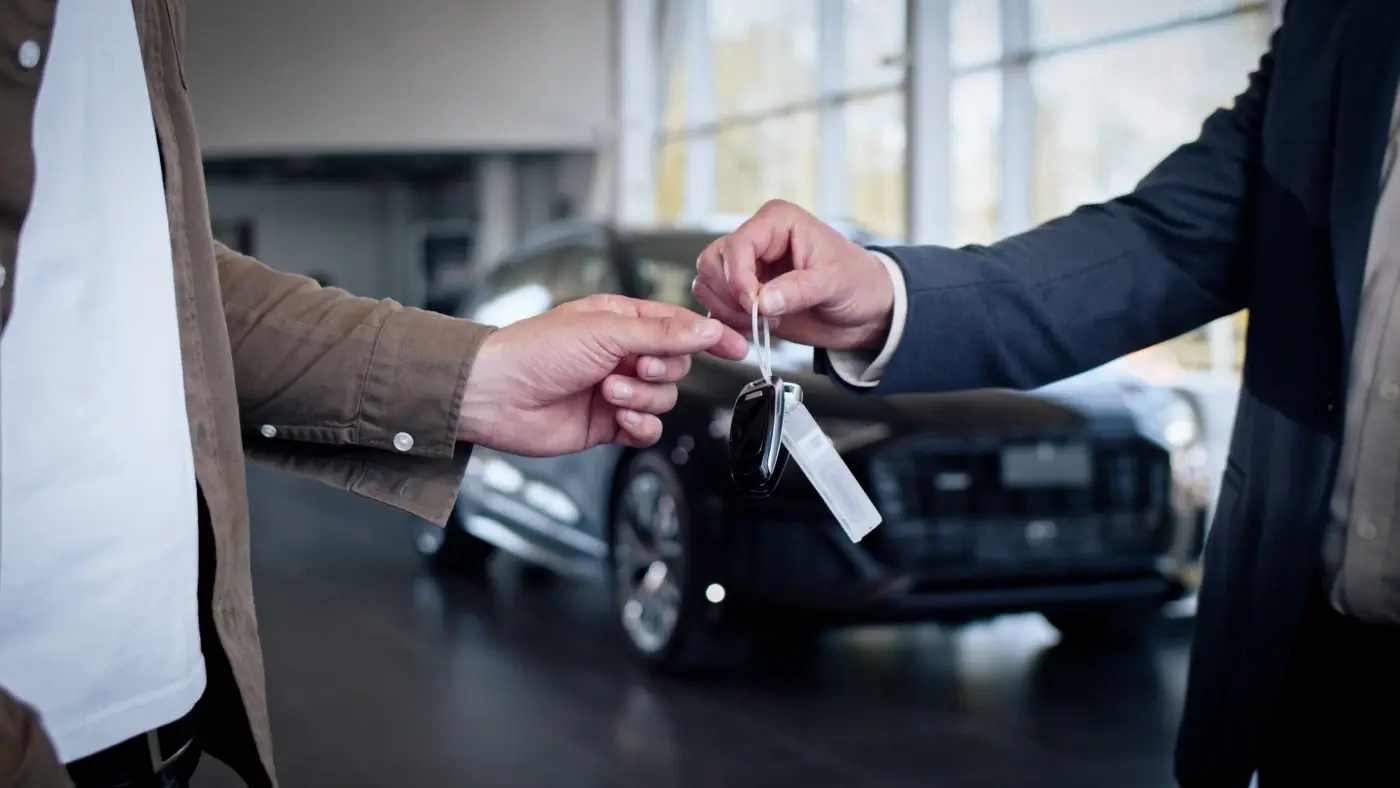 Male hand gives a car keys to male hand in the car dealership close up.