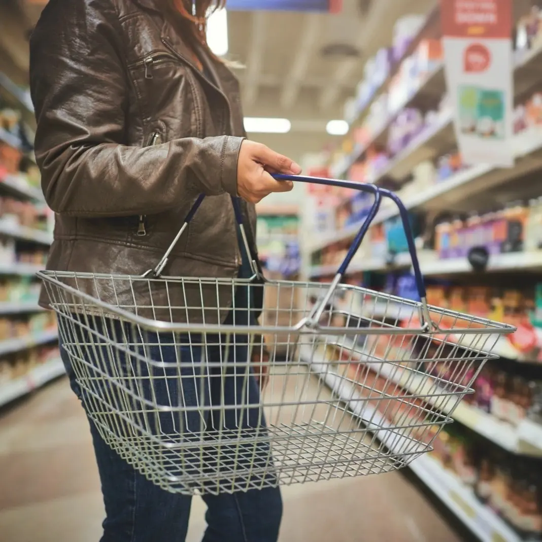 Photo of a store with a person holding a shopping basket