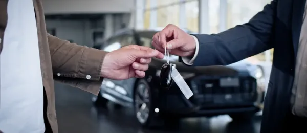 Male hand gives a car keys to male hand in the car dealership close up.