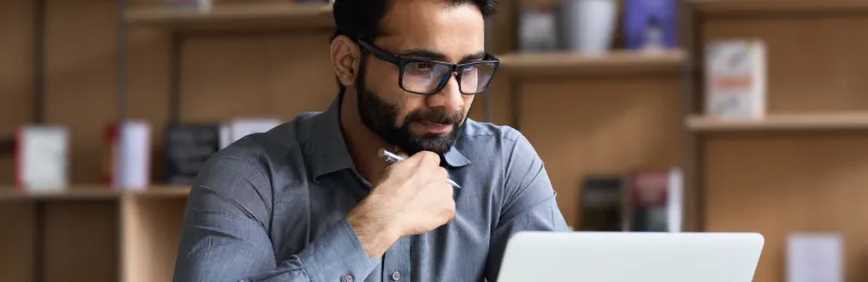 IT technician on a laptop in the library of a school