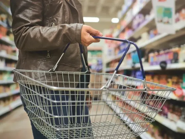 Photo of a store with a person holding a shopping basket